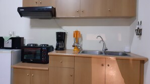 A compact kitchen with wooden cabinets, a microwave, a coffee maker, and a sink. - Hospitality Home in Asimi , with great location (HERAKLEION,GRETE)