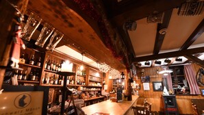 A cozy bar with wooden beams, shelves of bottles, and a rustic decor. - Pension Gimmelwald (Gimmelwald)
