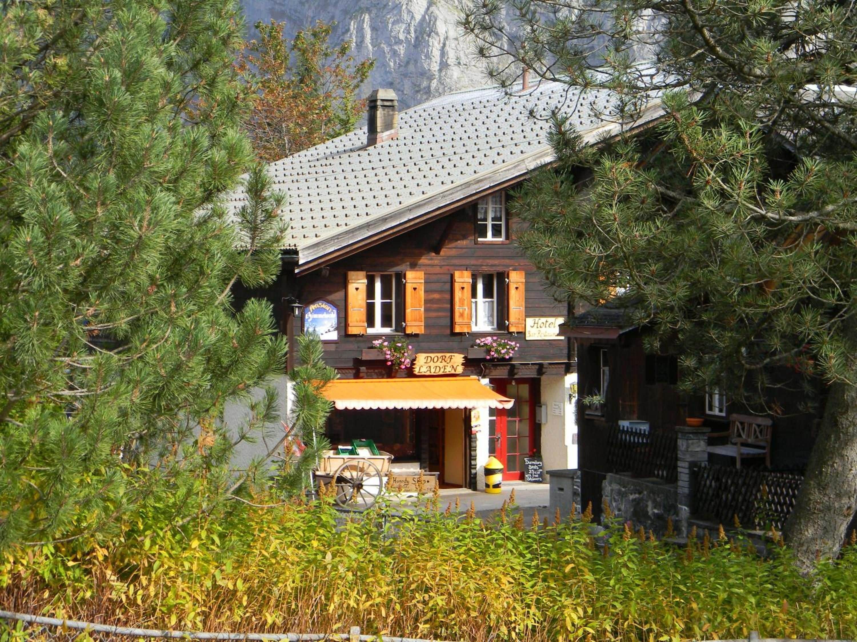 Un bâtiment en bois avec un toit en pente, une enseigne indiquant «Hôtel» et une entrée bien visible surmontée d’un auvent jaune.