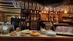A bar area with a wooden counter, various bottles, glasses, and a coffee machine. - Pension Gimmelwald (Gimmelwald)