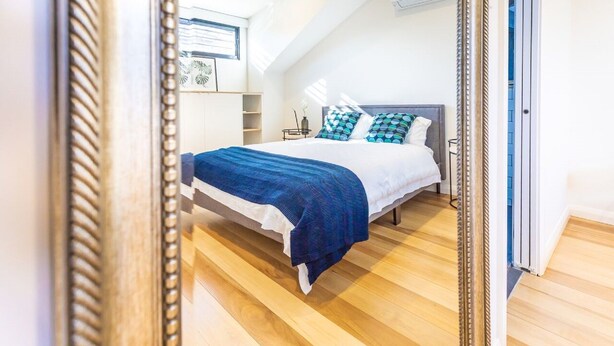 Ein Schlafzimmer mit Bett, Fenster und Spiegel.
