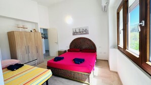 Ein Schlafzimmer mit einem Bett, einem kleinen Tisch, einem Kleiderschrank und einem Fenster mit Blick.