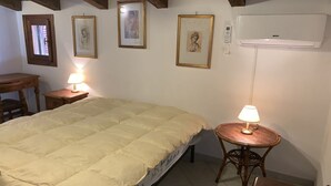 A bedroom with a bed, a bedside table with a lamp, a small round table with a lamp, and framed artwork on the wall. - I Geranei 3 San Teodoro Centro (San Teodoro)