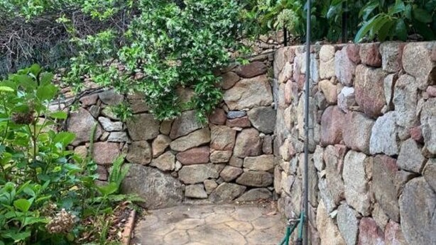 A stone wall with a metal structure, surrounded by greenery. - Appartamento Max con Giardino (Agrustos)