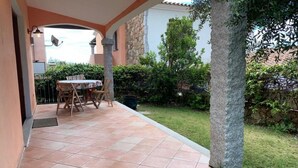 A patio with a table and chairs, surrounded by a stone wall and greenery. - Appartamento Max con Giardino (Agrustos)