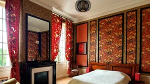 Ein traditionell eingerichtetes Zimmer mit Bett, Kamin, Sessel und großem Spiegel.