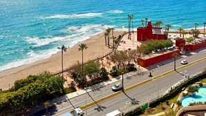 A coastal road with a beach, palm trees, and a red building with a tower. - Benalbeach Apartment with Magnificent Sea View (Benalmádena)