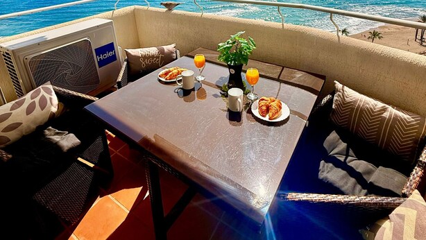 A balcony with a table set for breakfast, overlooking the ocean. - Benalbeach Apartment with Magnificent Sea View (Benalmádena)
