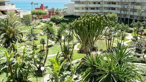 A hotel with a garden, palm trees, and a view of the sea. - Benalbeach Apartment with Magnificent Sea View (Benalmádena)