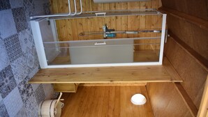 A wooden interior with a shower enclosure, a wooden bench, and a small white basin. - Charming caravan in a green setting near the beach (Vallauris)