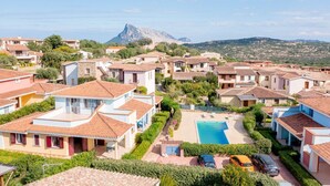 Un quartier résidentiel avec des maisons, une piscine et une montagne en arrière-plan.