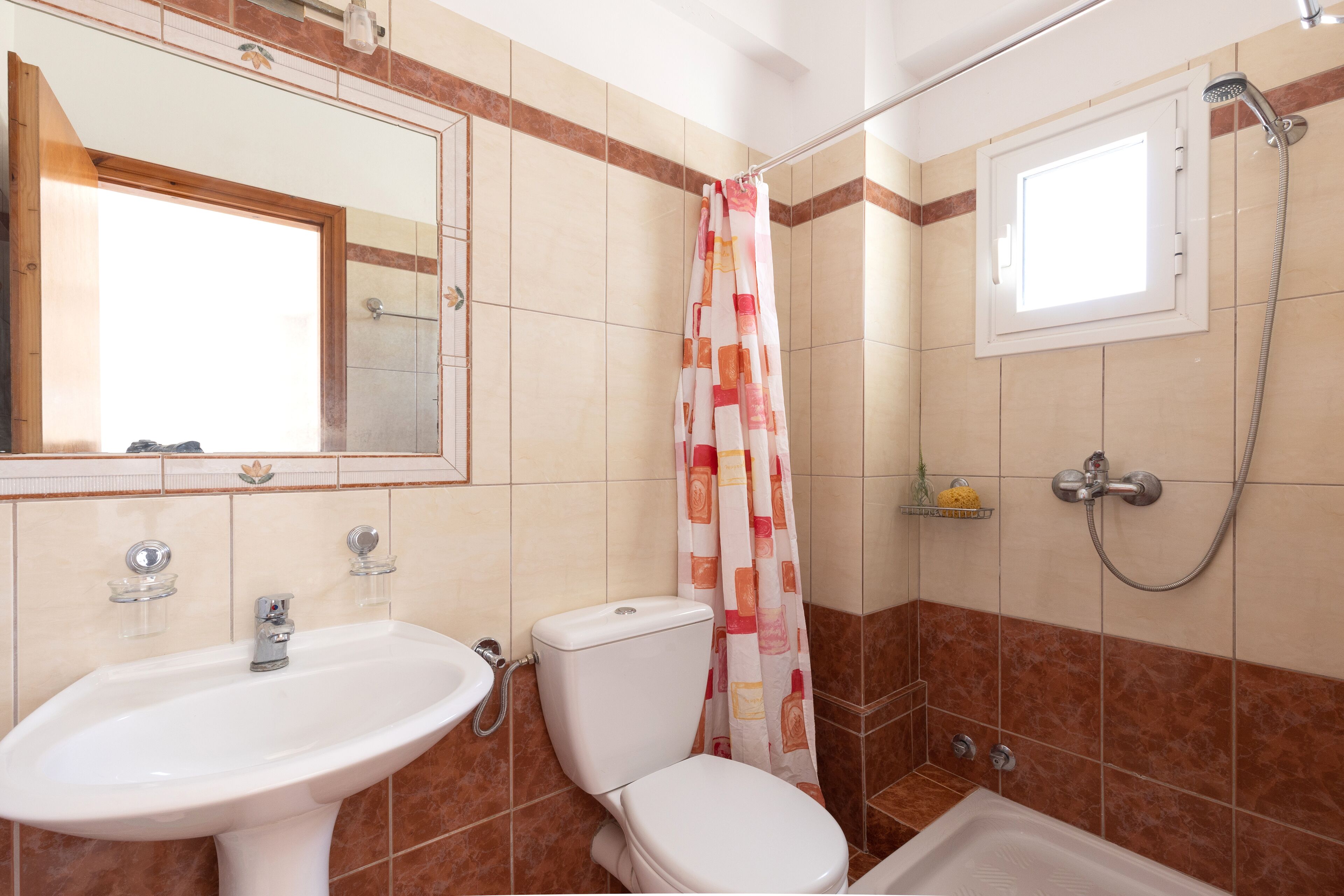 Un baño con lavamanos, inodoro, ducha y ventana.