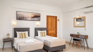 A hotel room with two beds, a desk, a chair, a lamp, and a painting on the wall. - Dora Pool Studios by Konnect, 150m from the Beach (Corfu)