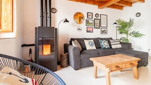 Una sala de estar acogedora con chimenea, un sofá con cojines decorativos y una mesa de centro de madera.
