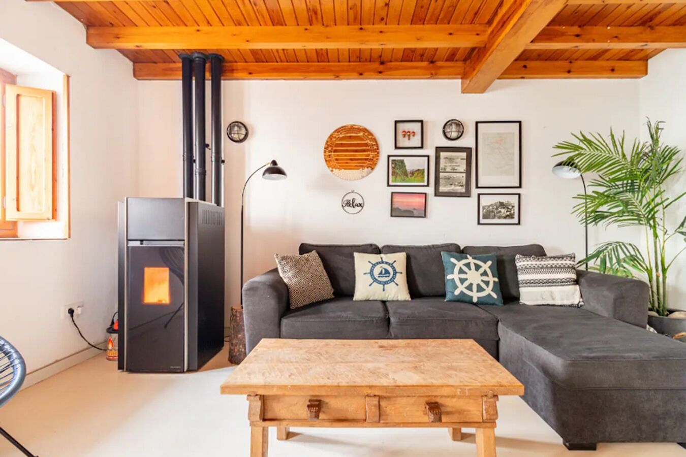 Un salon chaleureux avec un canapé gris foncé, une table basse en bois et un réfrigérateur noir.