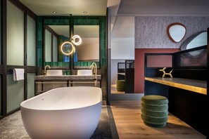 A modern bathroom with a freestanding bathtub, a vanity with a mirror, and a wooden floor.