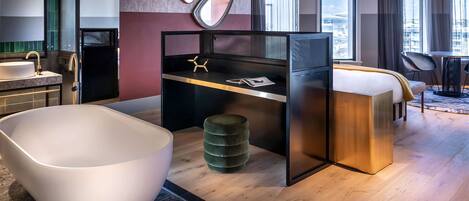 A modern hotel room with a large bathtub, a desk, and a view of the city.