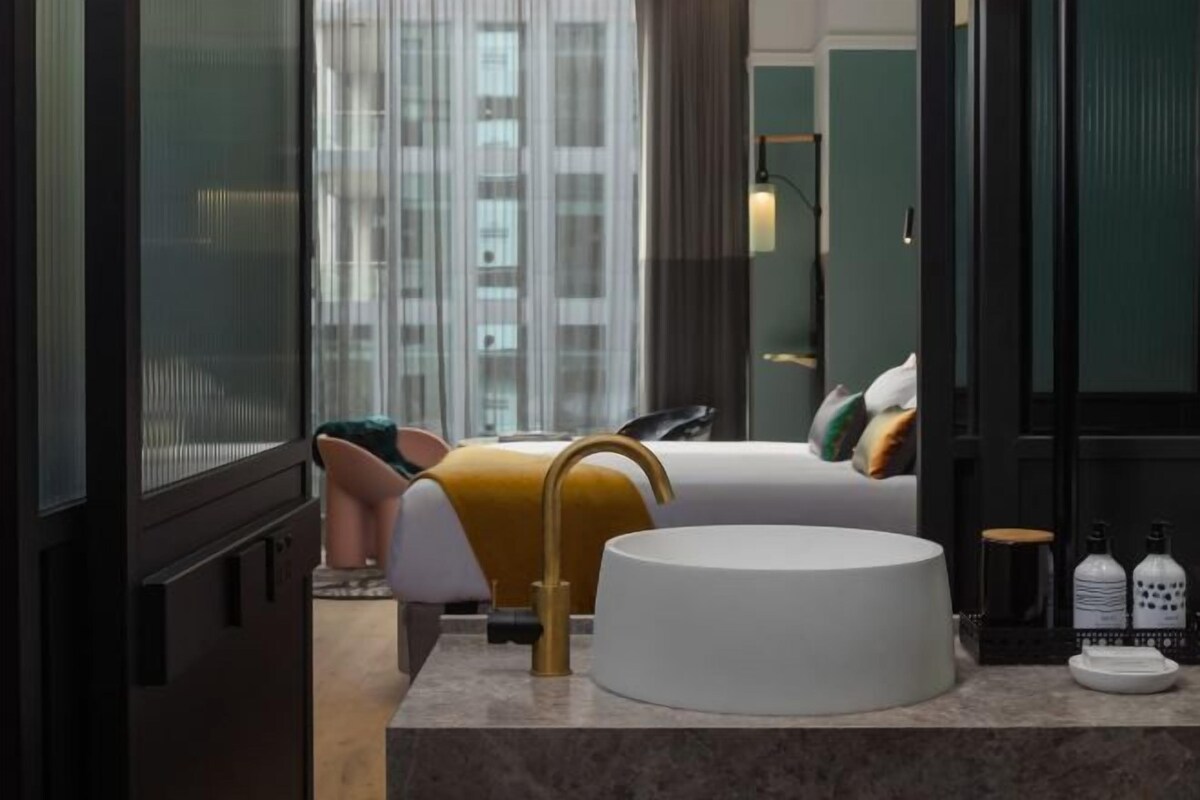 Une salle de bain moderne avec un grand lavabo, un miroir et une fenêtre équipée de stores.