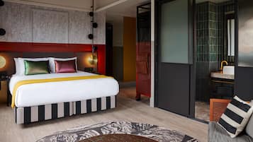 Een moderne hotelkamer met een groot bed, een aparte badkamer en een schuifdeur naar een balkon.