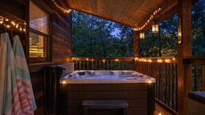 A wooden deck with a hot tub, benches, and string lights. - ♡♡ Cozy, Romantic Getaway w/Hot Tub & WiFi-Central Location (Sevierville)