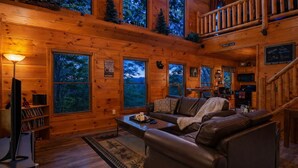 A cozy cabin interior with a leather sofa, a coffee table, and a TV. - ♡♡ Cozy, Romantic Getaway w/Hot Tub & WiFi-Central Location (Sevierville)