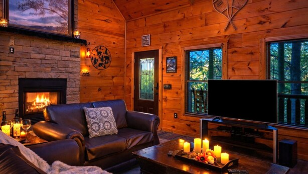 A cozy cabin interior with a fireplace, leather sofa, and a flat-screen TV. - ♡♡ Cozy, Romantic Getaway w/Hot Tub & WiFi-Central Location (Sevierville)