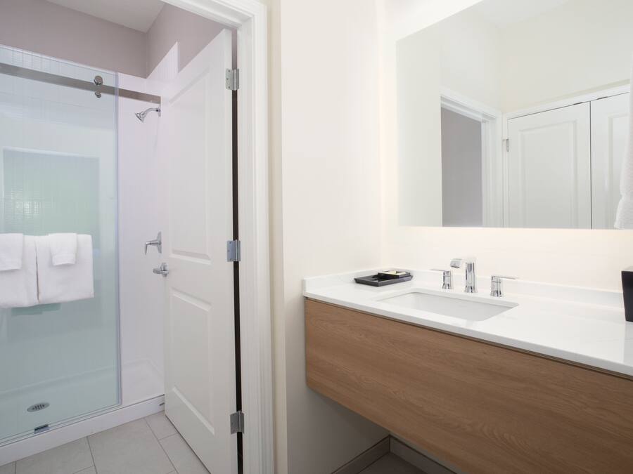 Ein modernes Badezimmer mit einer Duschkabine aus Glas, einem weißen Waschbecken und einem Holz-Waschtisch.