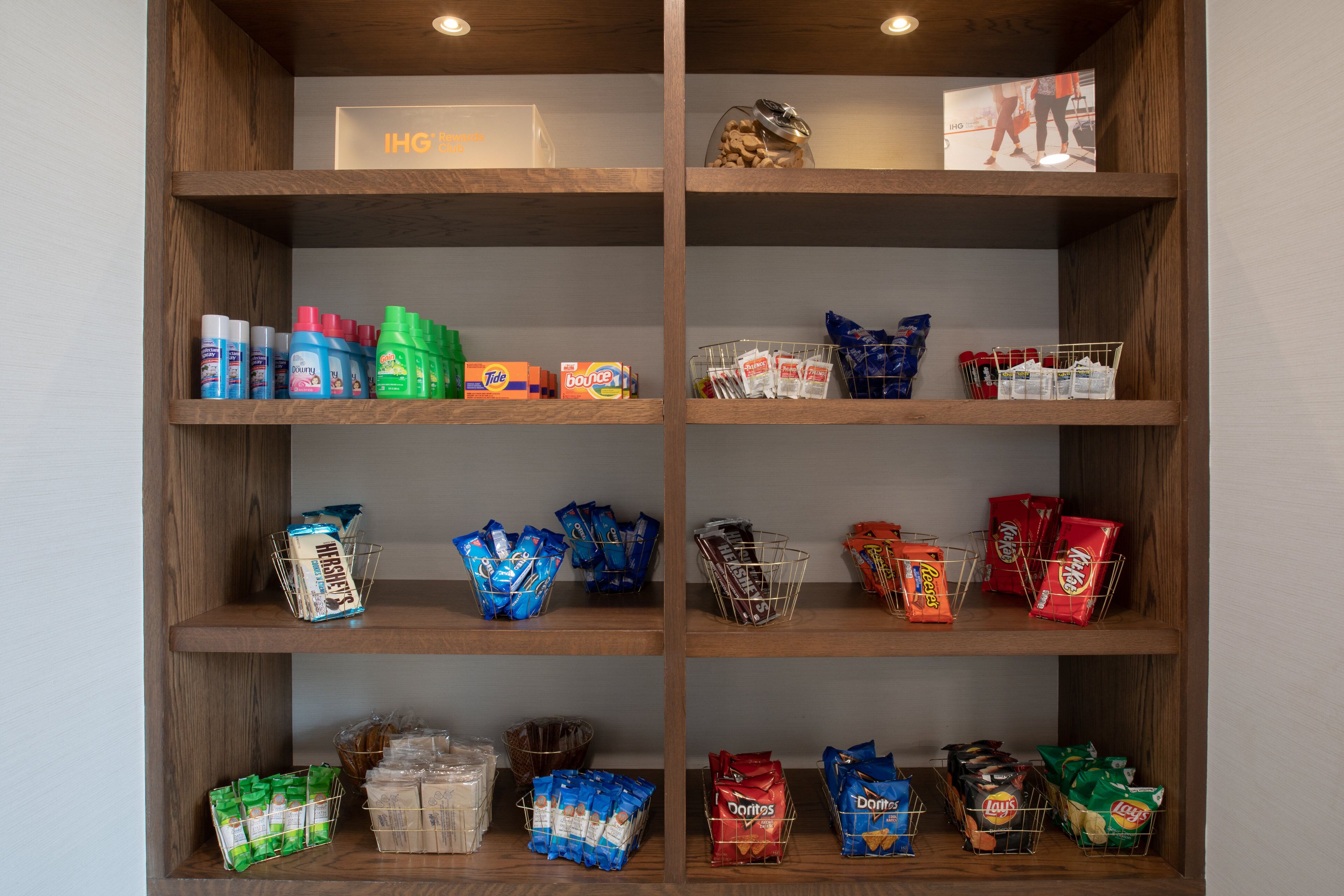 A wooden shelf unit with various snack items and beverages.