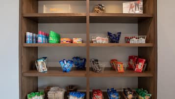 A wooden shelf unit with various snack items and beverages.