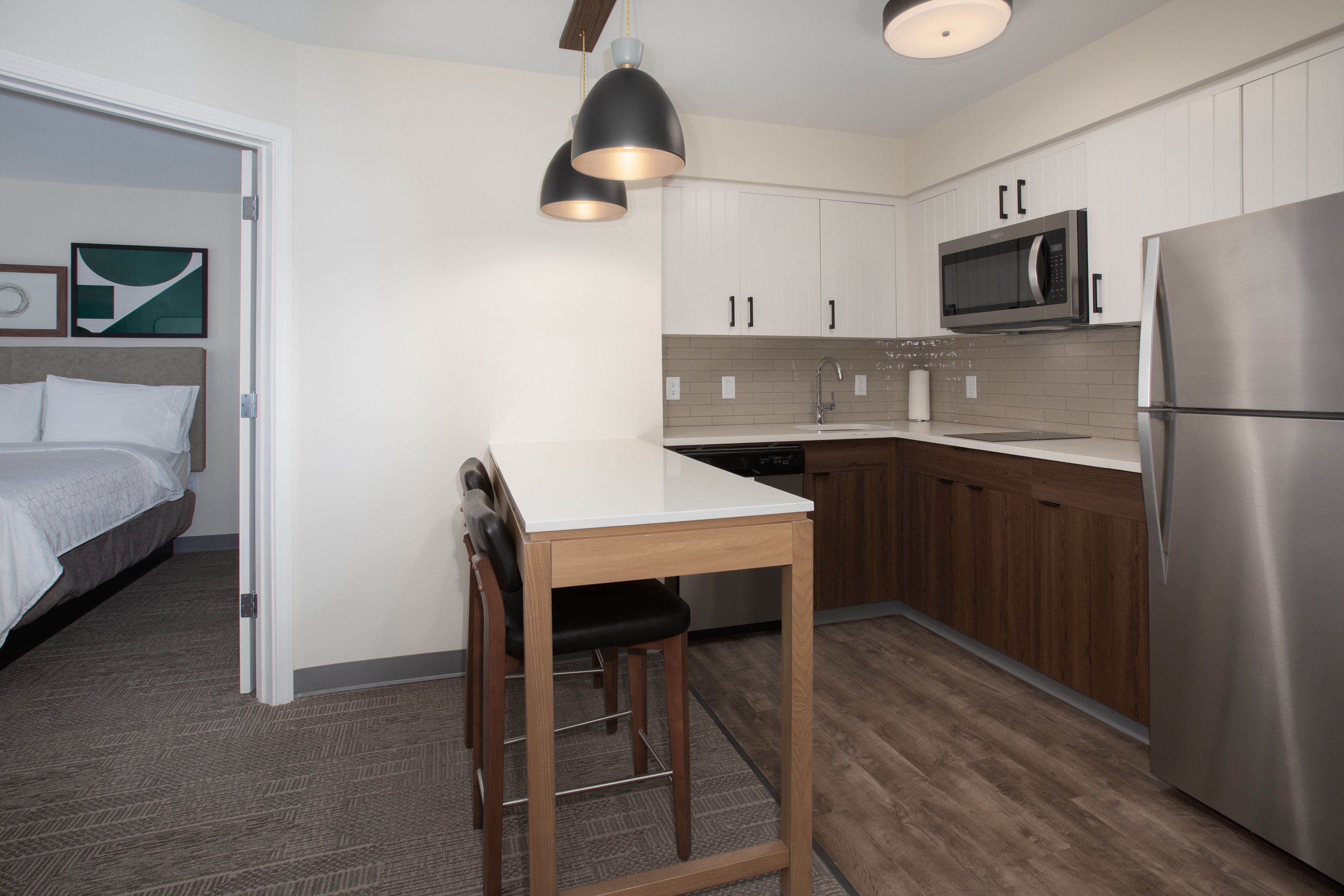 A modern kitchen with wooden cabinets, a stainless steel refrigerator, and a microwave.
