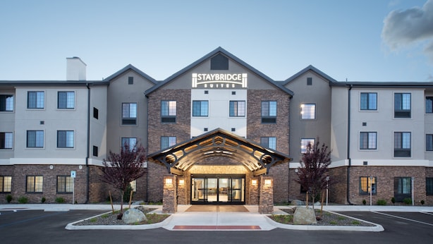 A Staybridge Suites hotel with a brick facade, large windows, and a prominent entrance with a covered walkway. - Staybridge Suites Carson City - Tahoe Area by IHG (Carson City)