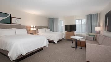 Une chambre d’hôtel avec deux lits, un canapé, une télévision et un bureau avec une lampe.