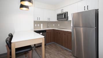 Una cocina moderna con armarios blancos, un refrigerador de acero inoxidable, un microondas y un lavavajillas.