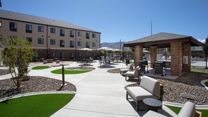 An outdoor patio area with seating, a barbecue station, and a building in the background. - Staybridge Suites Carson City - Tahoe Area by IHG (Carson City)