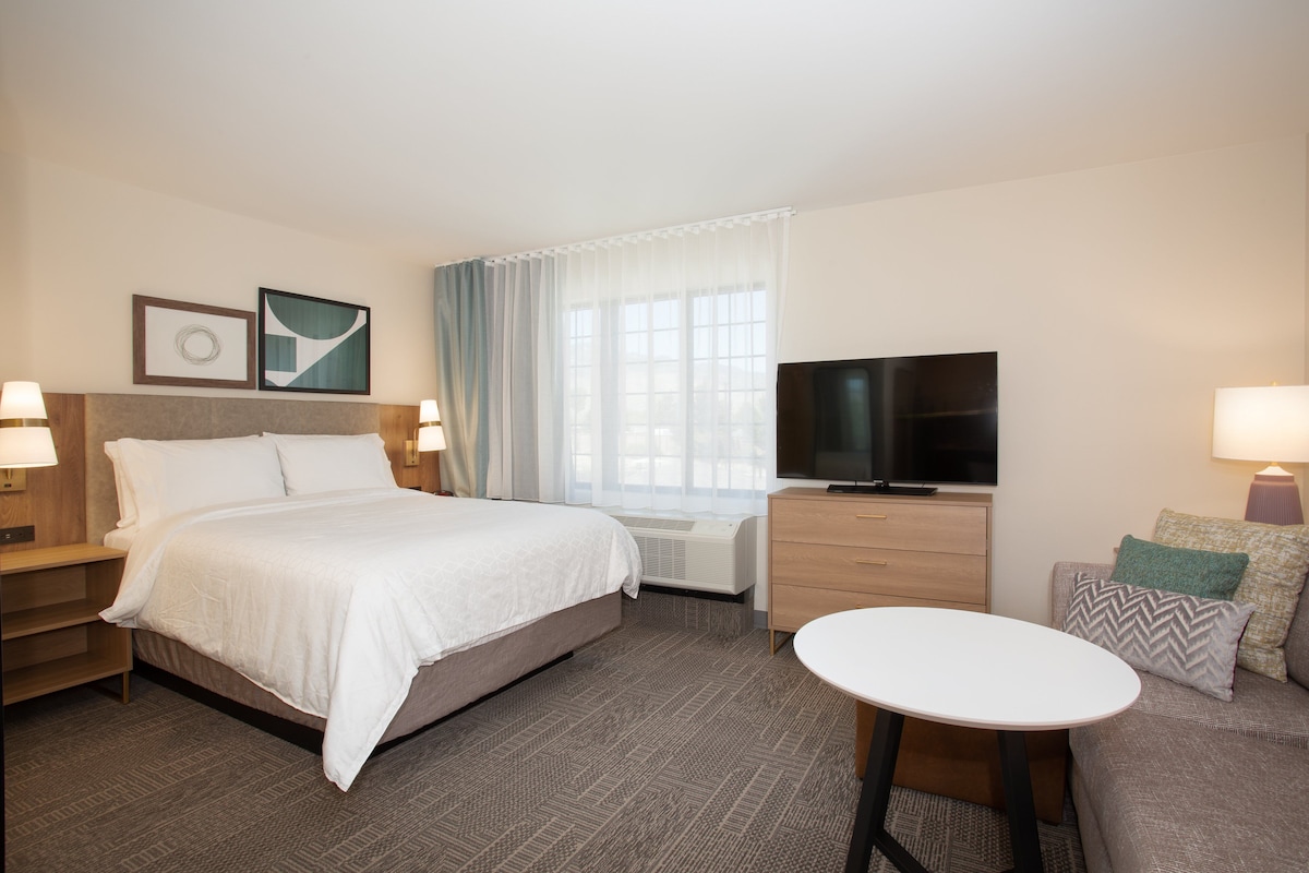 A hotel room with a bed, a TV, a desk, and a chair.