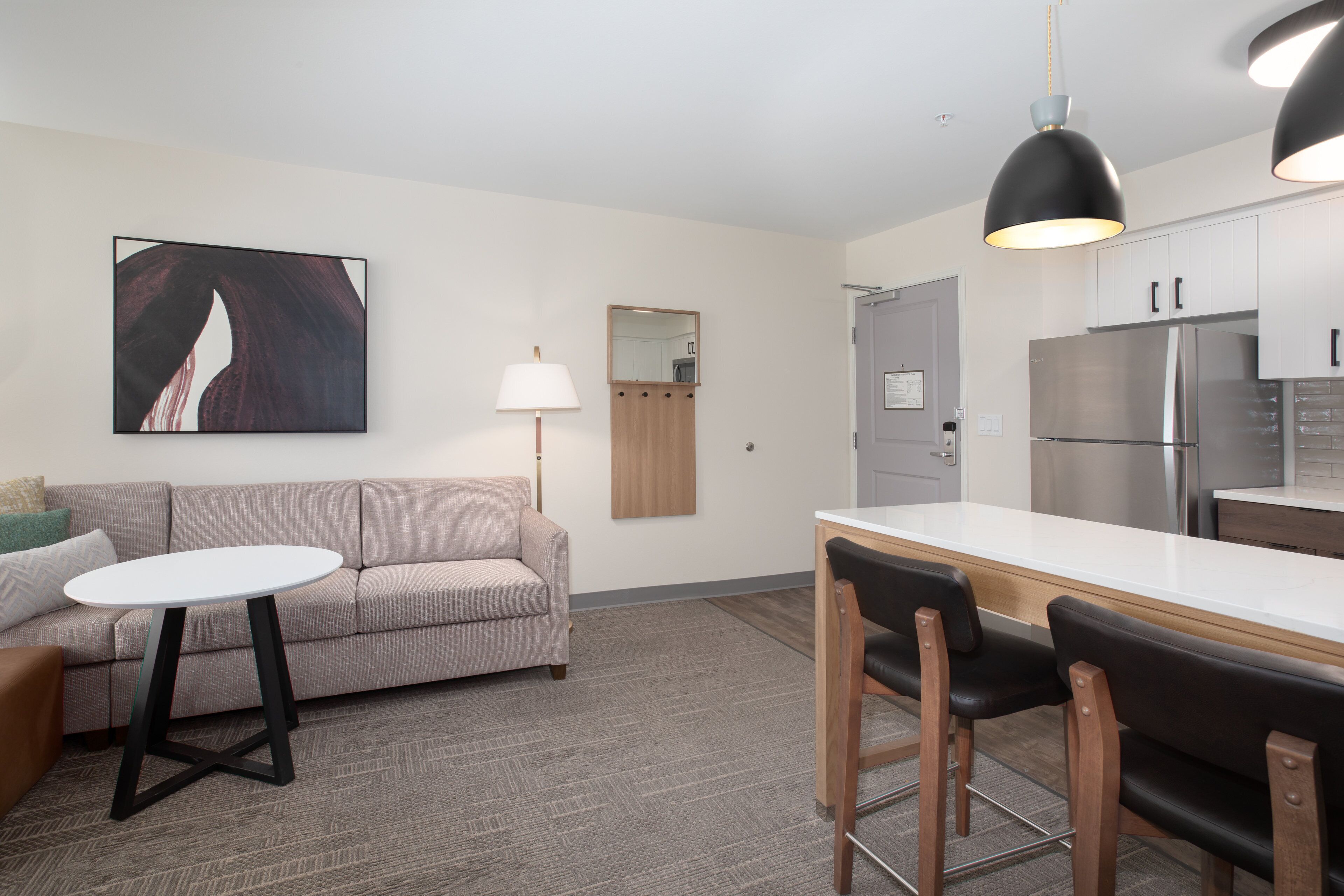 A modern kitchen with a white countertop, stainless steel appliances, and a dining area with a round table and chairs.
