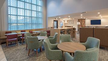 A hotel lobby with a seating area, a reception desk, and a large window providing natural light.