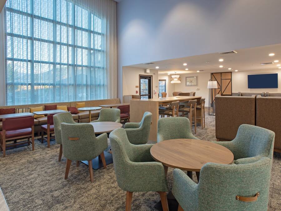 A hotel lobby with a seating area, a reception desk, and a large window providing natural light.