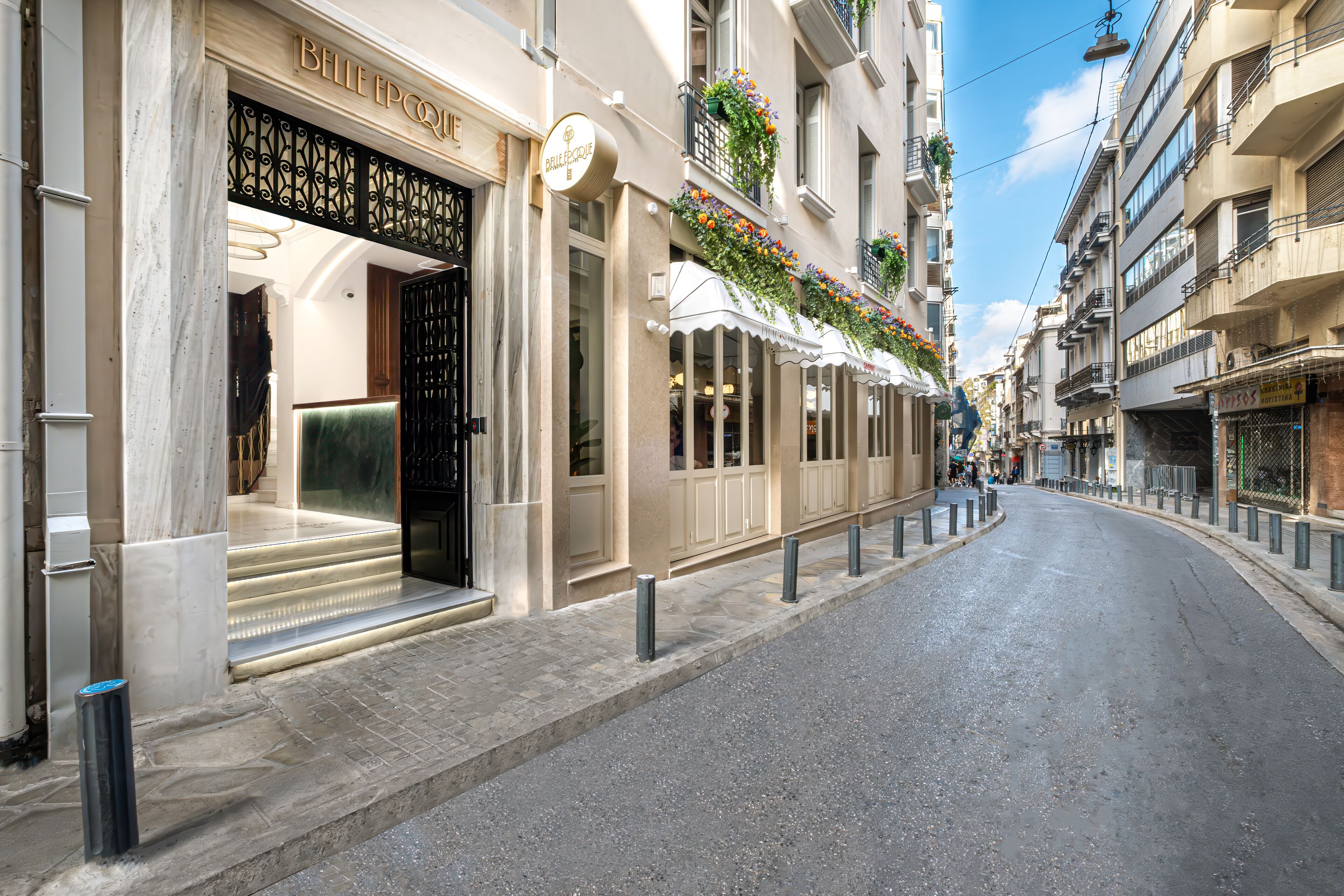 Une vue de rue d’un immeuble avec l’entrée d’un hôtel-boutique, un trottoir dégagé et une allée piétonne.