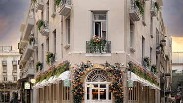 A multi-story building with balconies, a central entrance with a decorative arch, and outdoor seating.