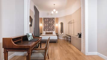A bedroom with a wooden desk, a bed, a mirror, and a wardrobe.
