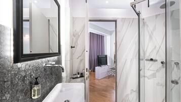 Un baño moderno con un lavabo de mármol, cabina de ducha con mampara de vidrio y un espejo sobre el lavabo.