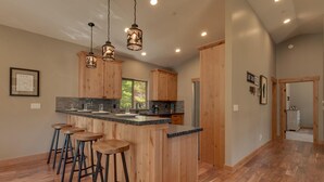 Una cucina moderna con mobili in legno, un piano di lavoro in granito e sgabelli da bar.