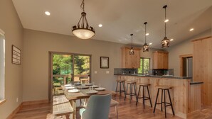 Una cucina moderna con mobili in legno, un'isola centrale con sgabelli e illuminazione a sospensione.