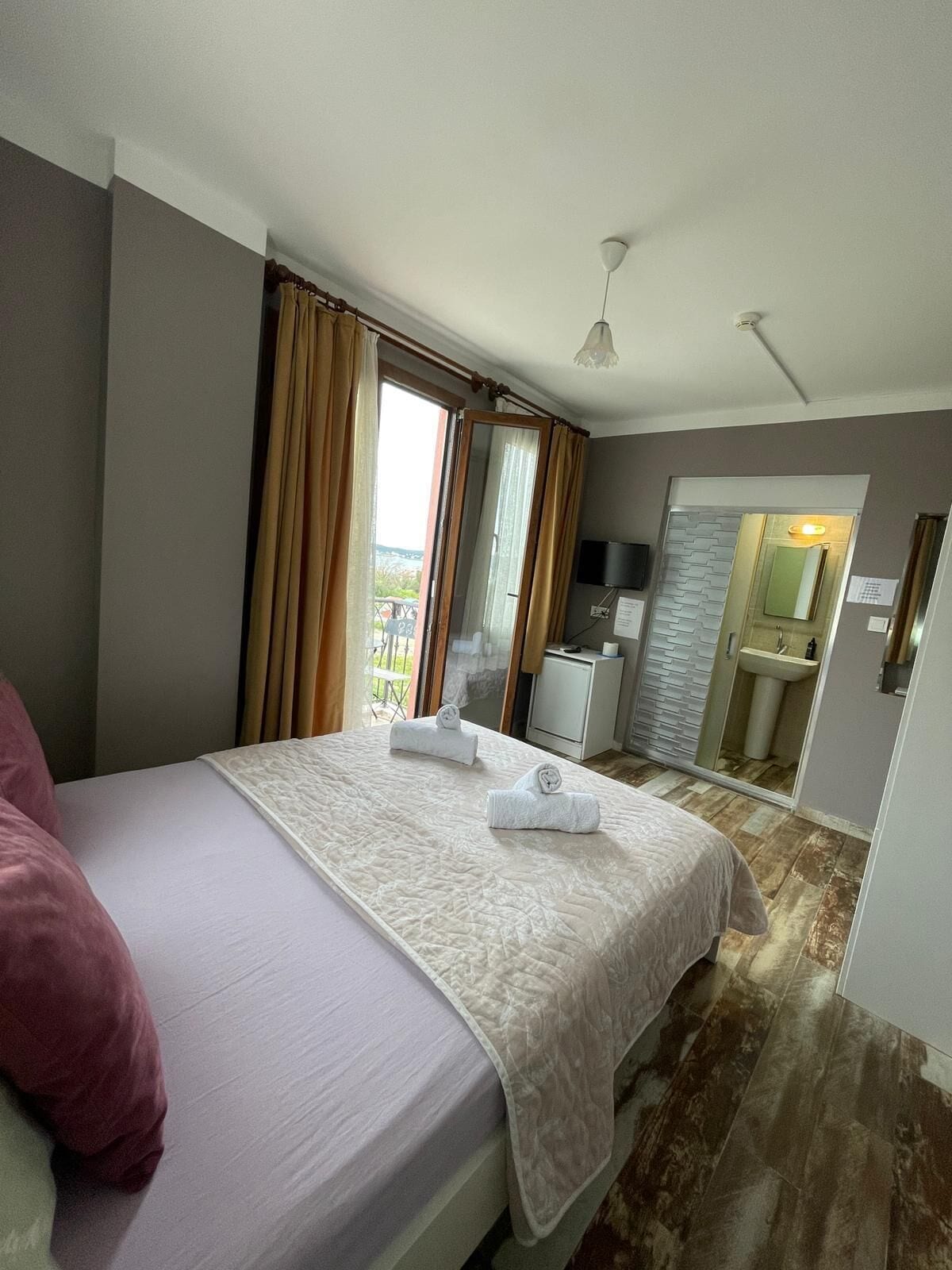A hotel room with a bed, a desk, a mirror, and a bathroom visible through an open door.