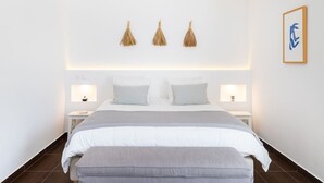 A modern bedroom with a large bed, bedside tables, and wall-mounted lighting. - Amazing Comporta family beach house (Comporta)