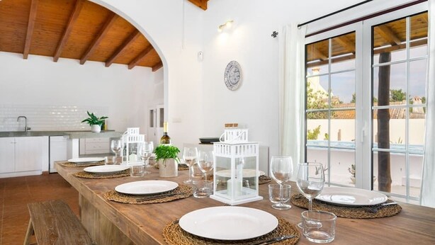 A dining area with a long wooden table set for four, white plates, and clear glasses. - Amazing Comporta family beach house (Comporta)