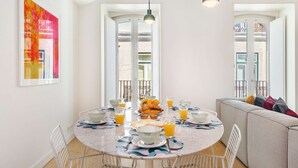 A modern dining area with a round table set for breakfast, featuring croissants and orange juice.