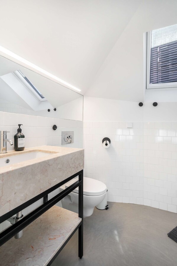 Un baño moderno con lavamanos de mármol, inodoro y tragaluz.