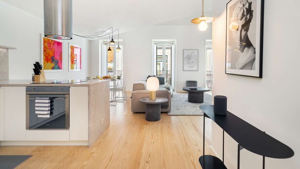 A modern kitchen with a central island, a dining area with a round table, and a living space with a sofa and a coffee table.